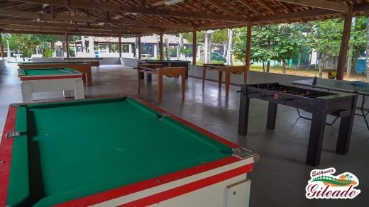 Área coberta com mesas de sinuca e jogos
